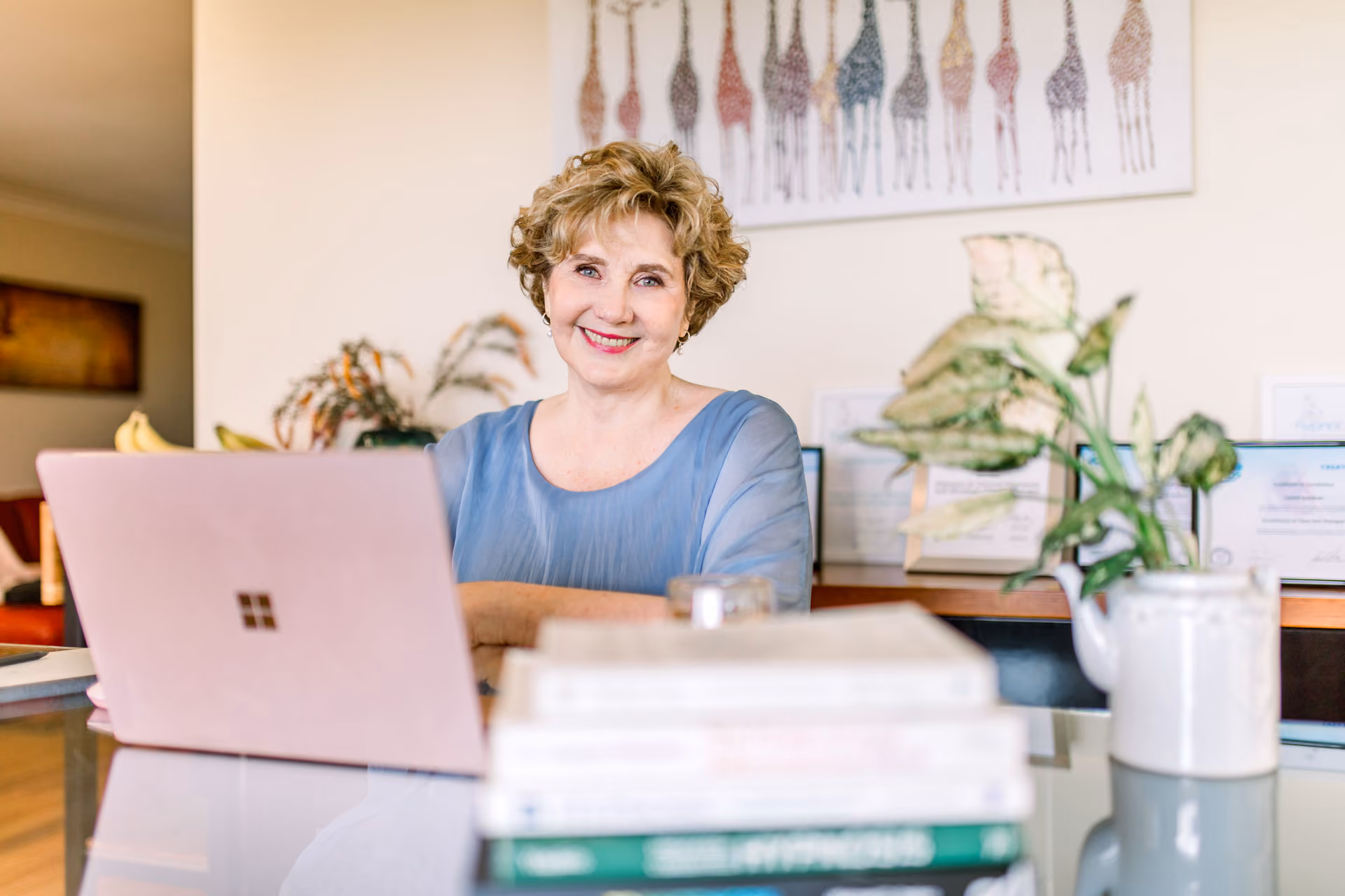Lynne Gardner smiling during an online hypnotherapy consultation at her office
