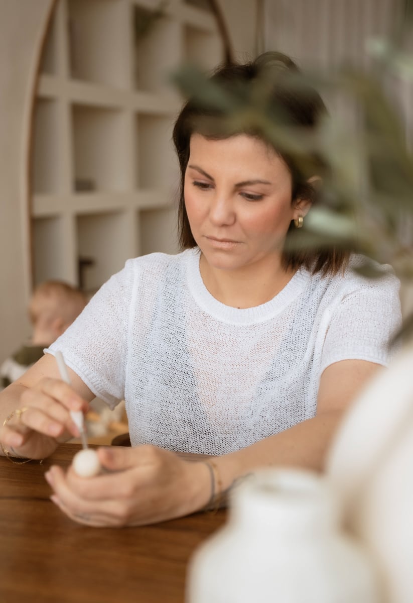 Dominique werkt aan tafel met een kind op de achtergrond.