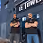 Deux hommes debout côte à côte, les bras croisés devant le restaurant Le Tower.