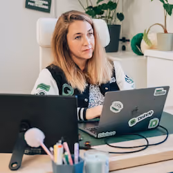 Femme travaillant sur ordinateur portable dans un bureau avec plantes et fournitures de bureau.