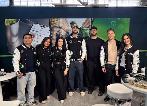 Équipe Dishop debout souriant, portant des vestes noires et blanches avec des logos verts.