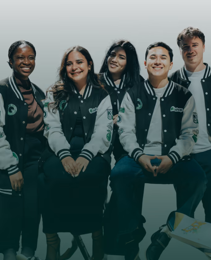 Groupe de cinq jeunes souriants, portant des vestes assorties noires et blanches avec logos, posant ensemble devant un fond clair.