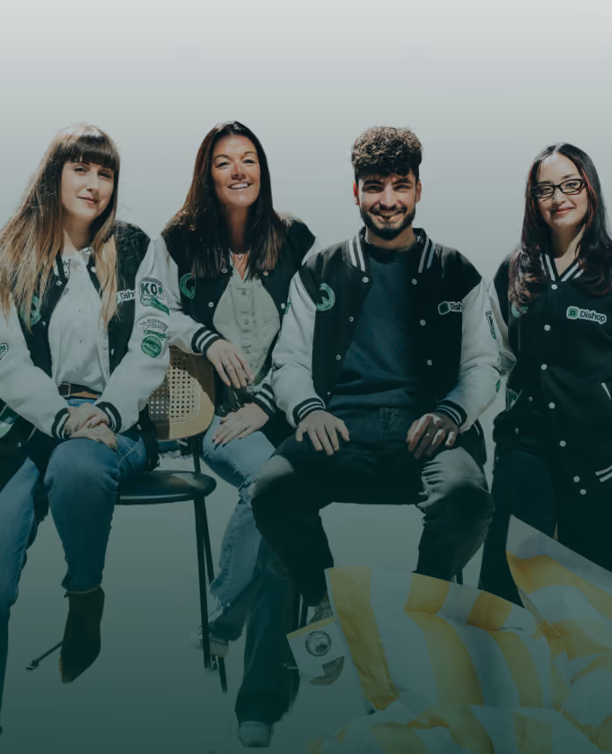 Quatre jeunes adultes assis, portant des vestes universitaires noires et blanches, souriant et posant devant un fond clair.