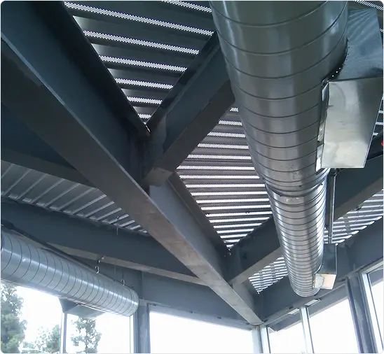 Exposed spiral HVAC ductwork running beneath a steel roof structure