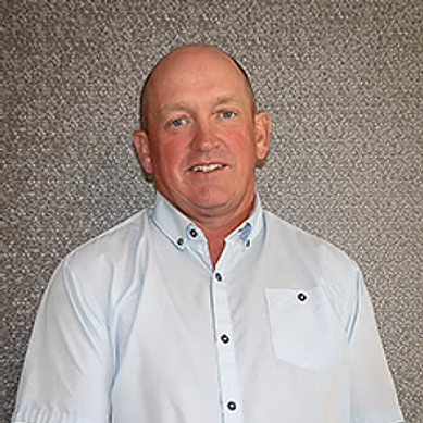 Middle-aged man with shaved head wearing a light blue button-up shirt against a gray textured background.
