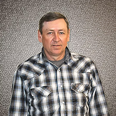 Middle-aged man in a black and white plaid shirt standing against a textured gray background.