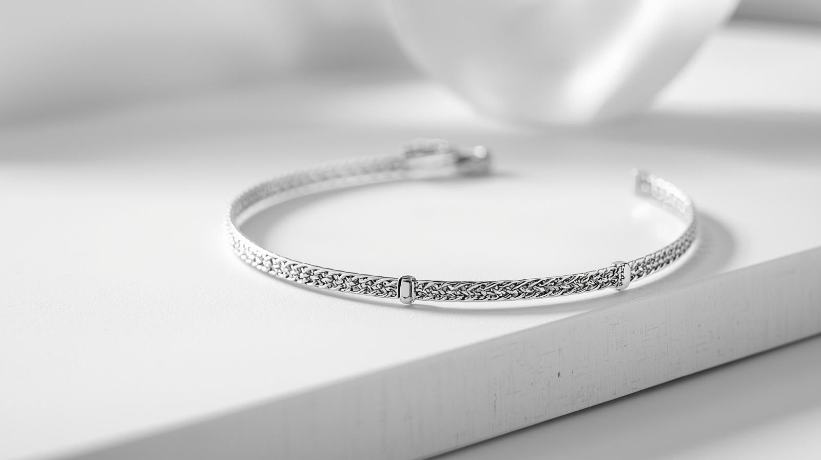 Elegant silver chain bracelet displayed on a white surface under soft lighting.
