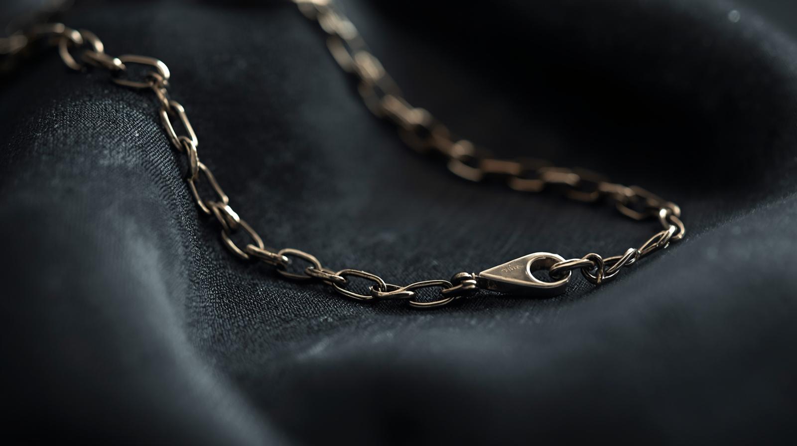 Close-up of a sterling silver necklace chain resting on a black fabric background.