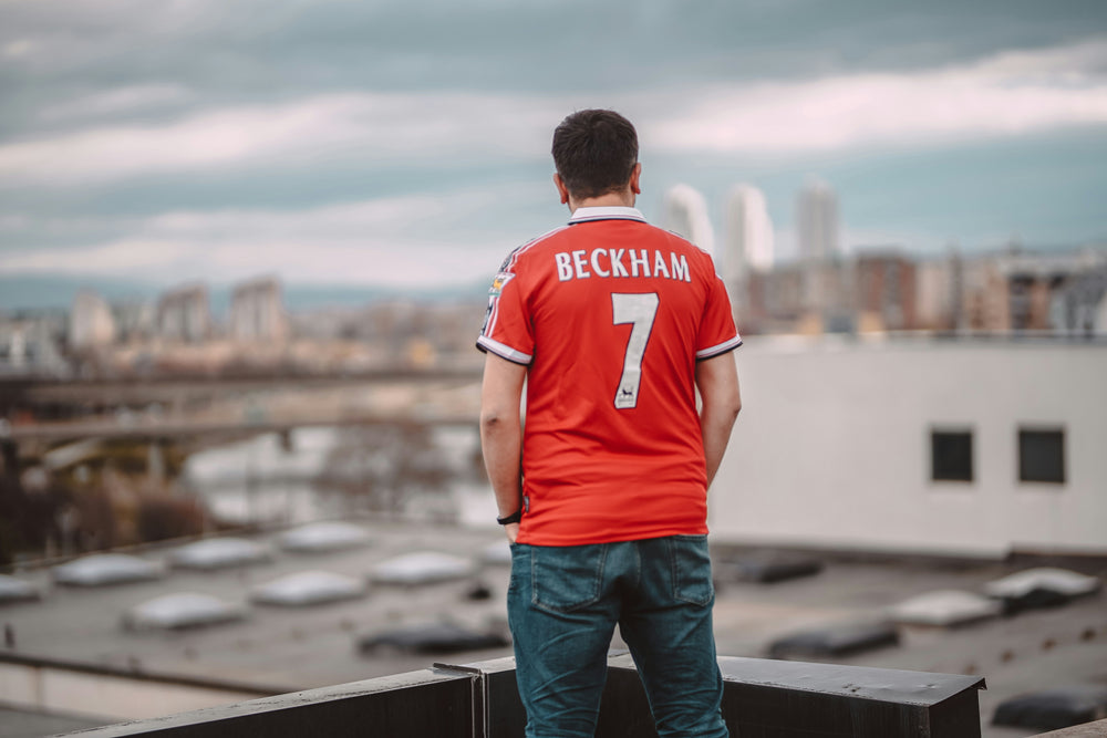 A man wearing a Beckham soccer jersey and jewelry