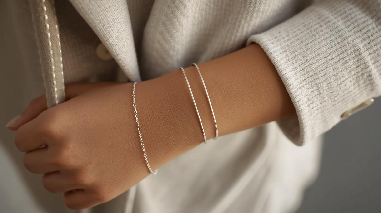 Minimalist silver bracelets styled on a woman’s wrist with a neutral outfit for an elegant everyday look.