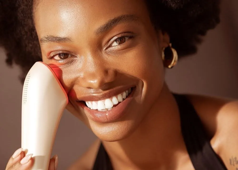 A woman holding a skin laser up to her face.