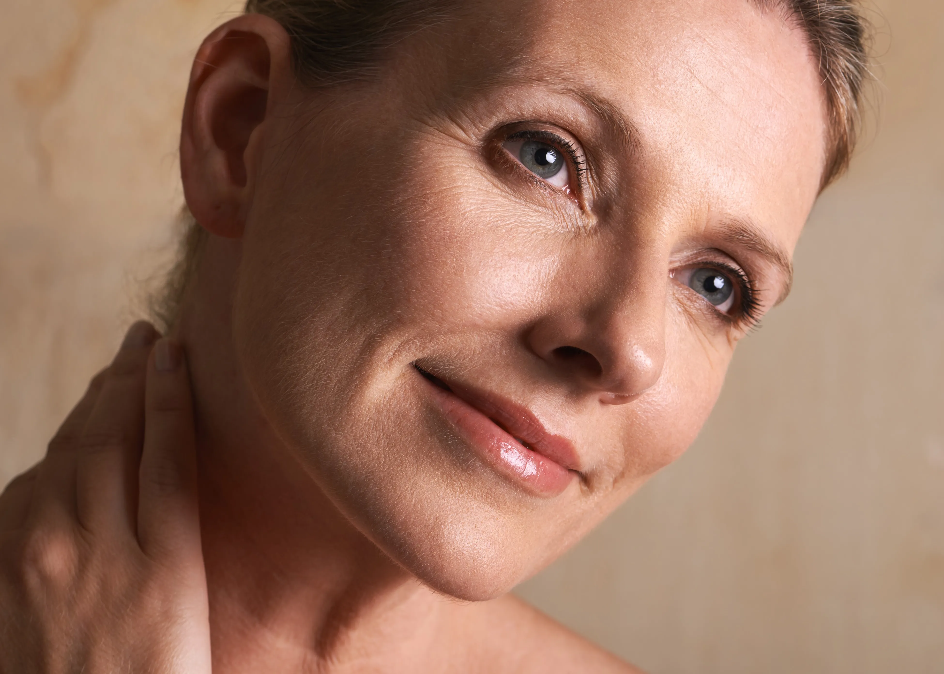 A close up of a woman with her hand on her neck.