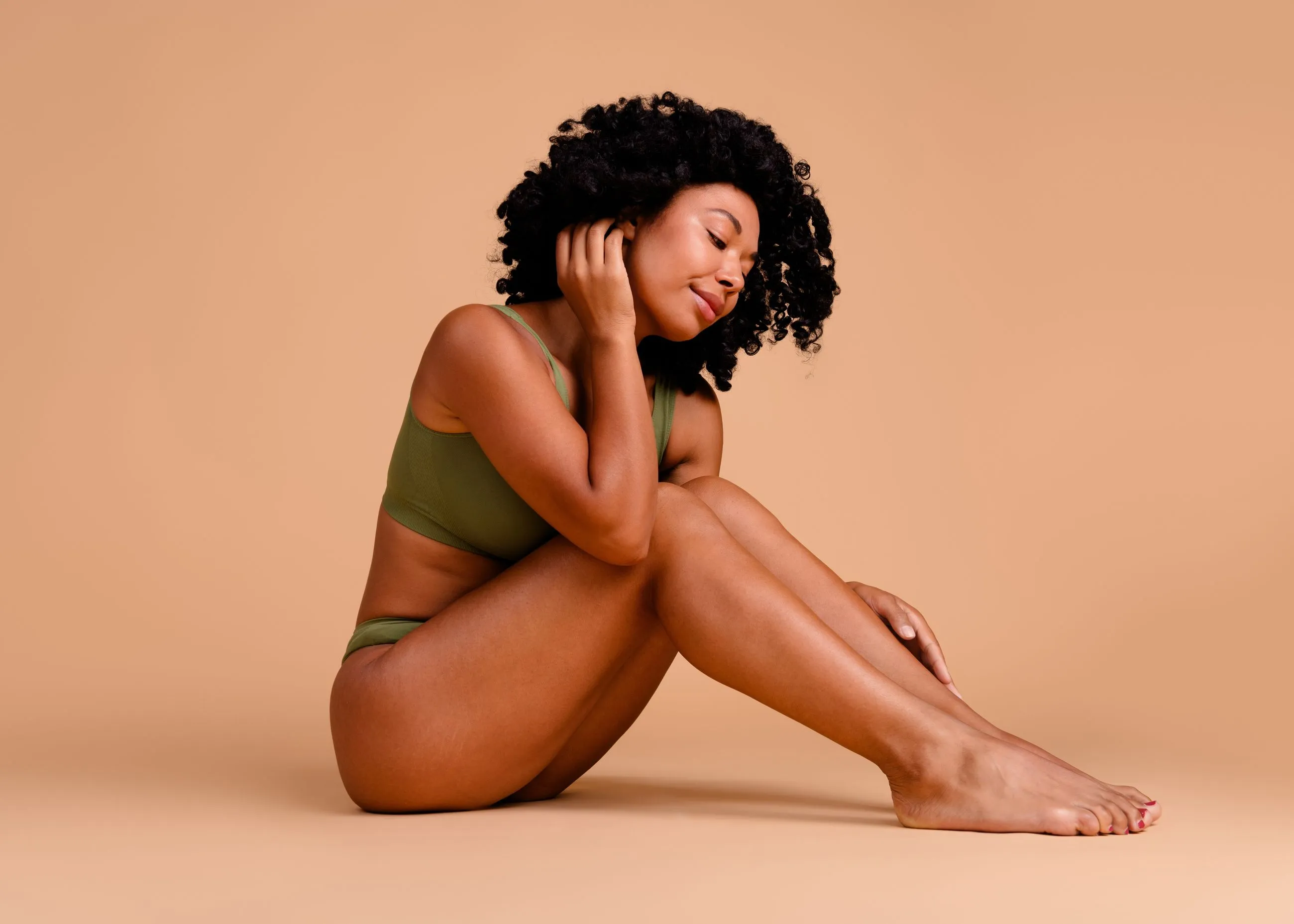 A woman sitting on the ground with her legs crossed.