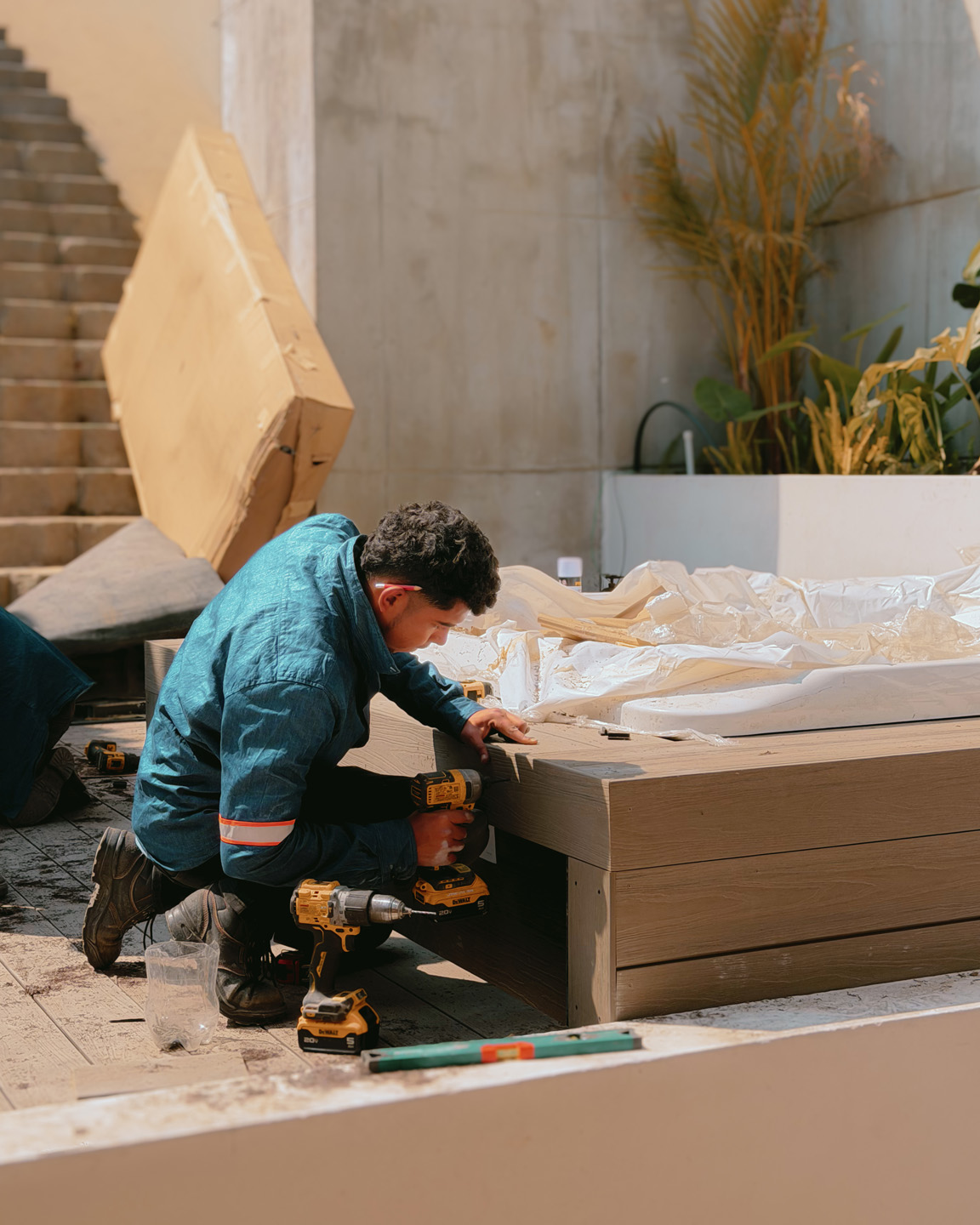 Hombre usando taladro eléctrico mientras trabaja en estructura de madera cerca de escaleras.