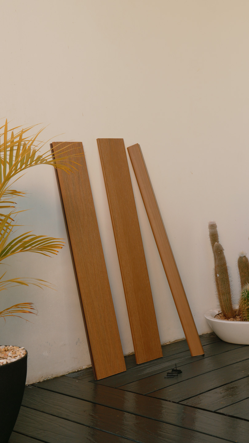 Tres paneles de madera apoyados contra una pared, con plantas en macetas a ambos lados.