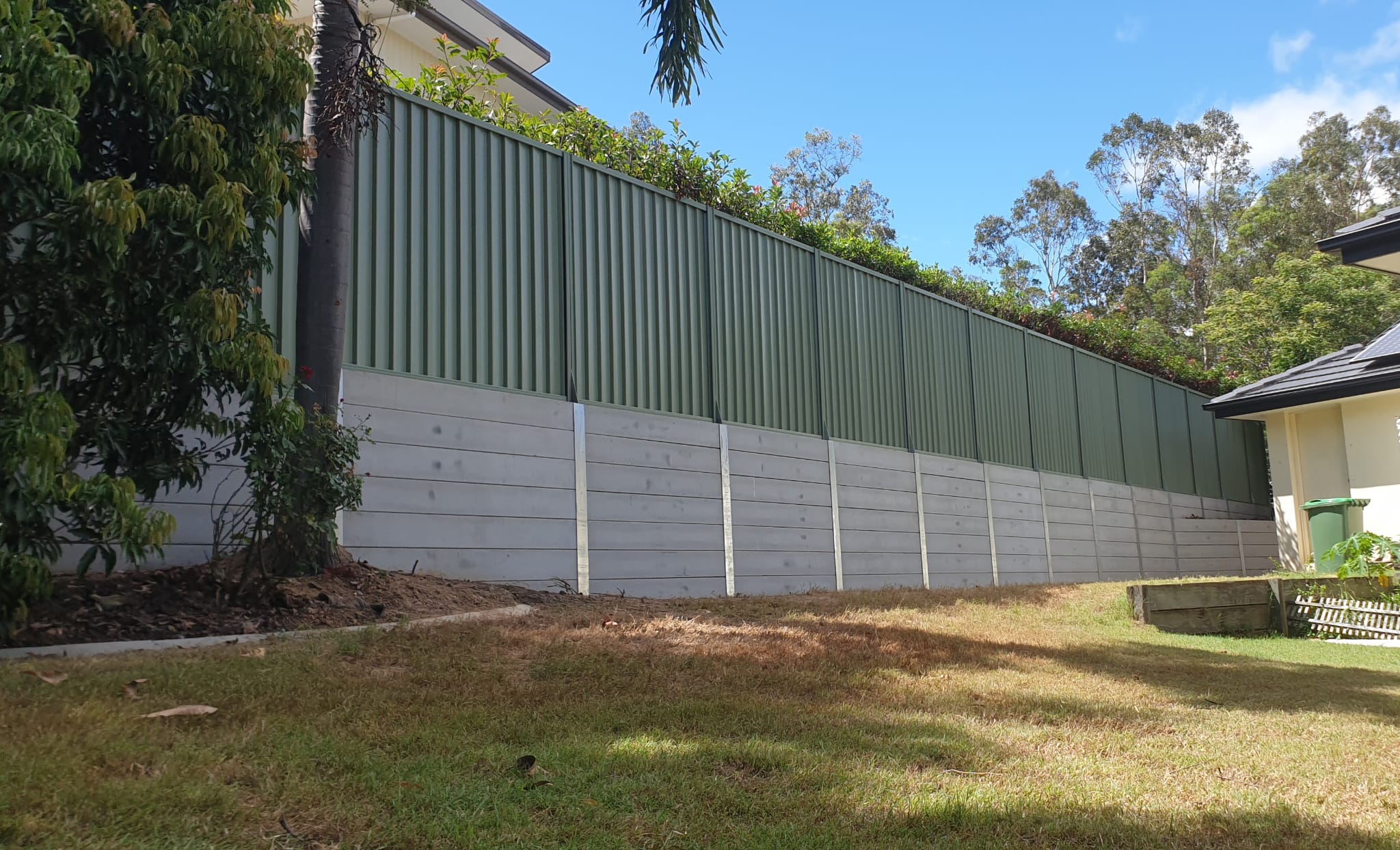Concrete sleeper retaining wall on galvanised steel posts, built by Synergy Fencing in Brisbane