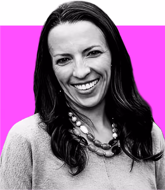 Black and white photo of woman with long hair smiling, wearing a sweater and necklace, pink background.