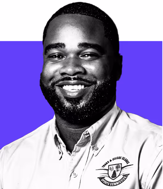 Smiling man with short hair and beard wearing a light shirt with a logo on purple and white background.
