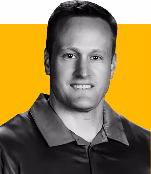 Smiling man in a collared shirt with short hair against a yellow and white background.