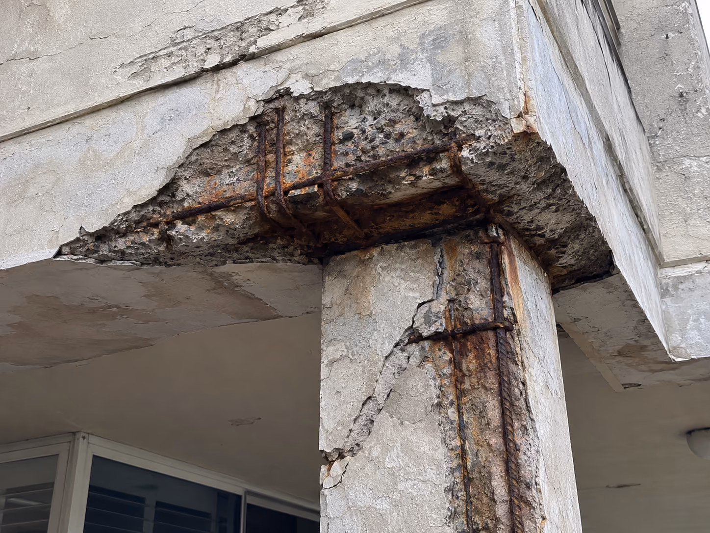 Corroding steel reinforcement bar exposed along the edge of a concrete slab