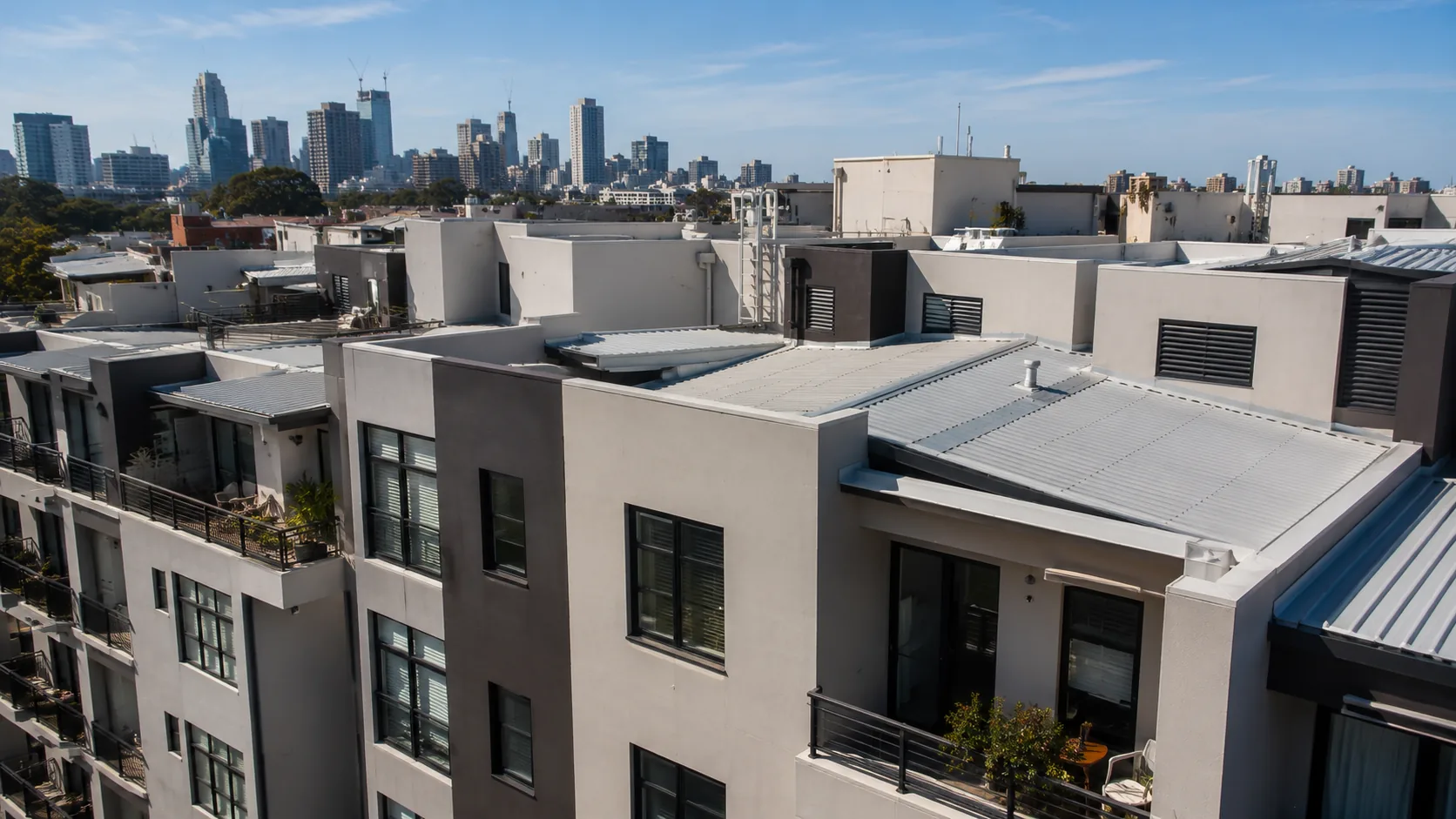 Complex apartment rooftops and level changes with the Sydney skyline beyond