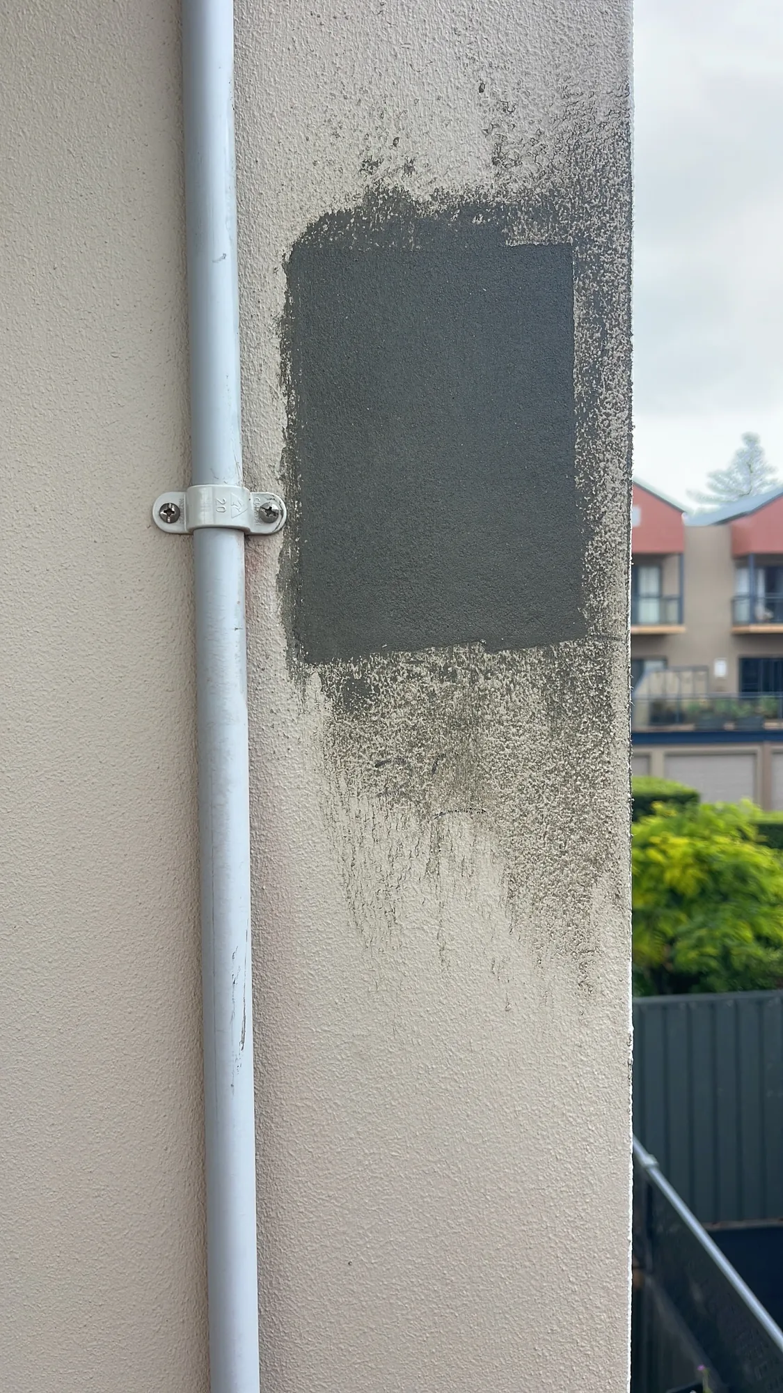 Grey render patch applied over prepared facade section, repair in progress