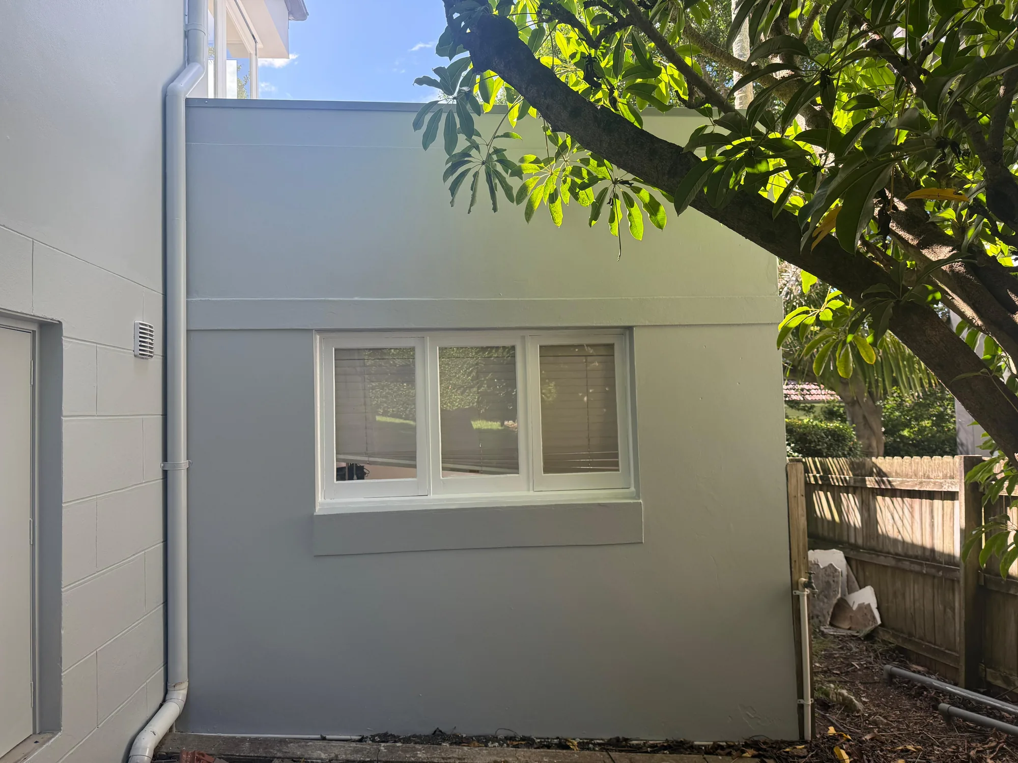 Rendered exterior wall and window reveal repaired and repainted pale grey after facade works, Sydney