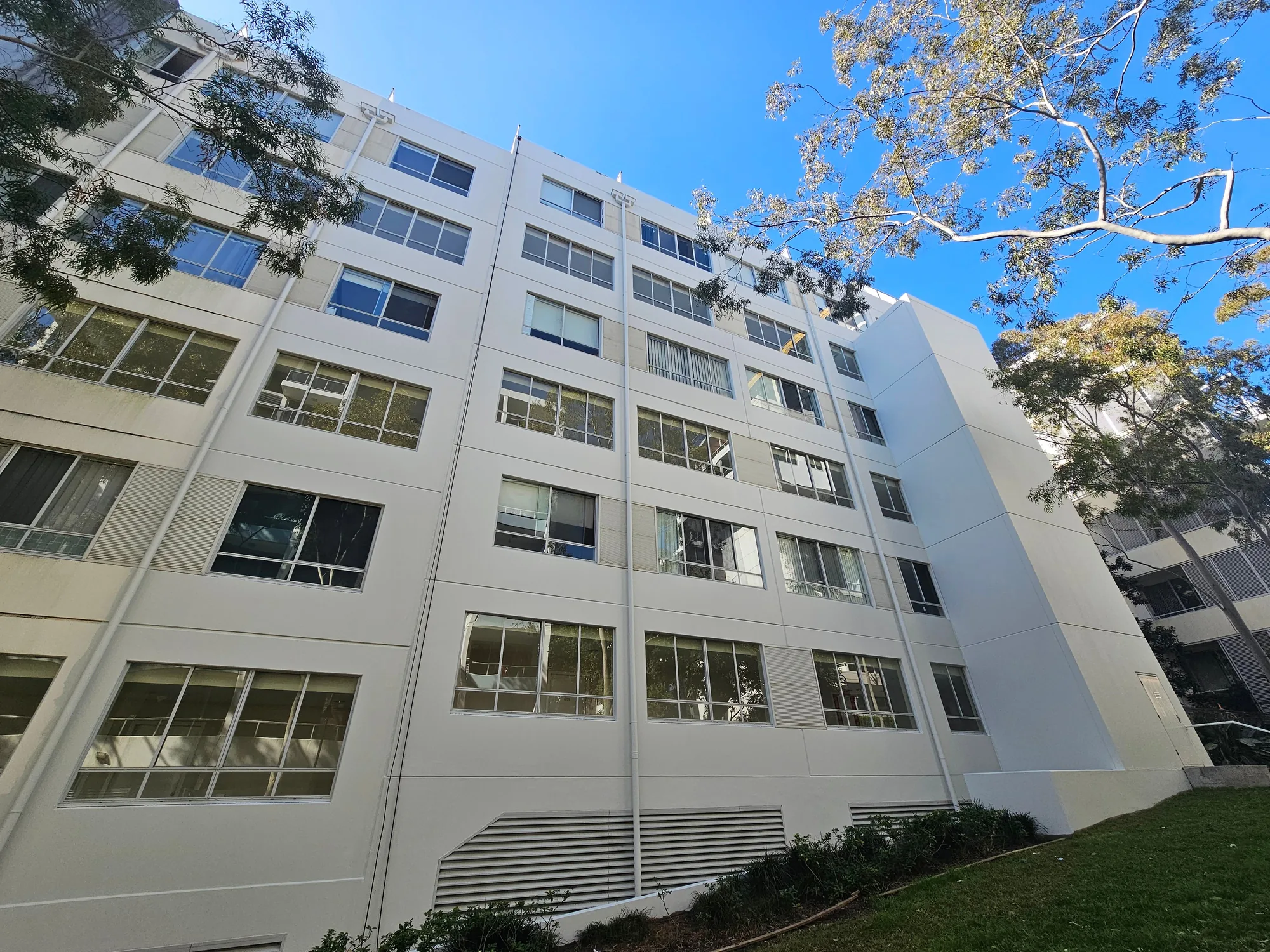 Multi-storey rendered residential facade repainted white after facade works, Sydney