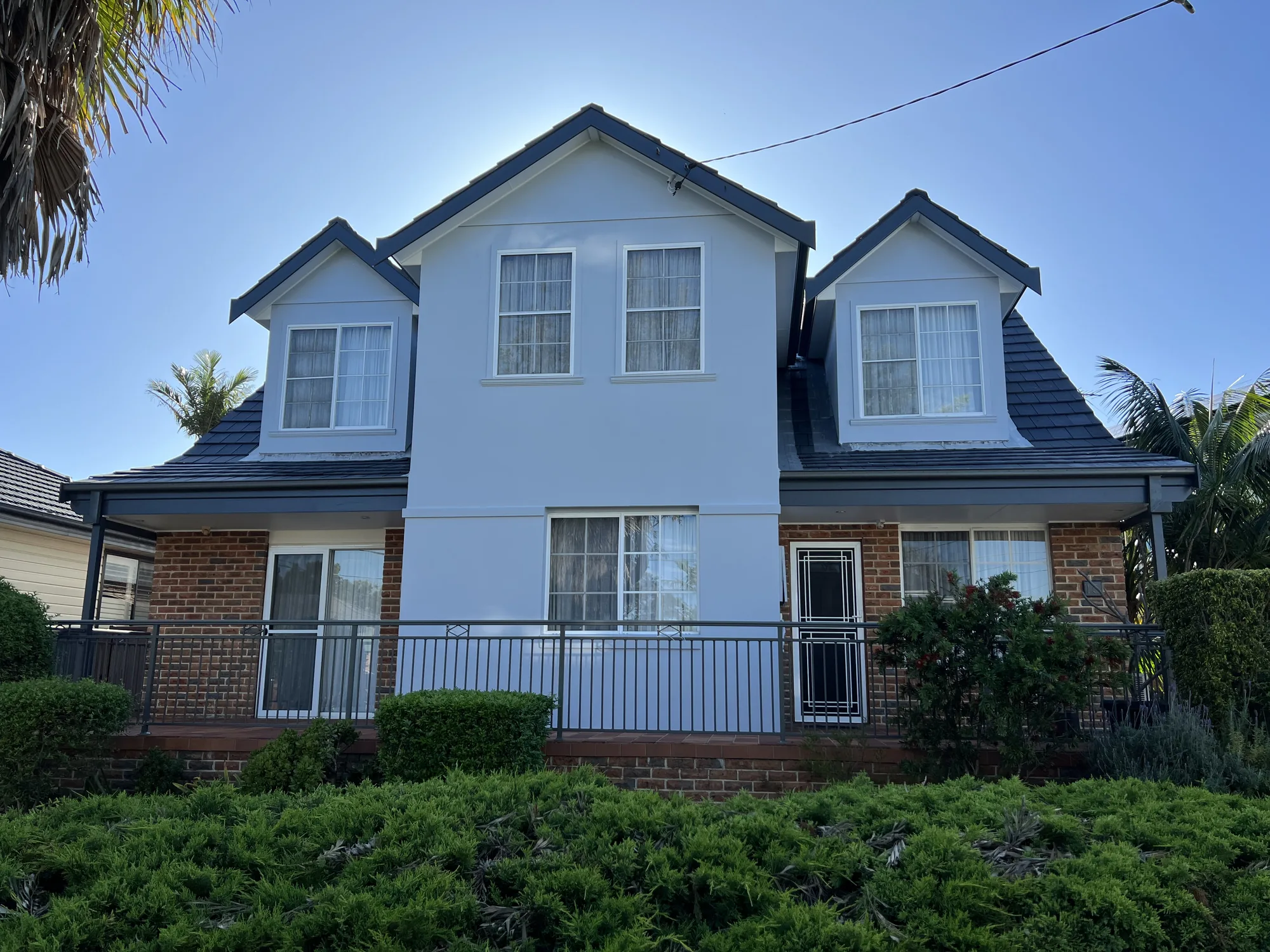 Two-storey brick-and-render home repainted white with charcoal trim after exterior painting, Eastern Suburbs