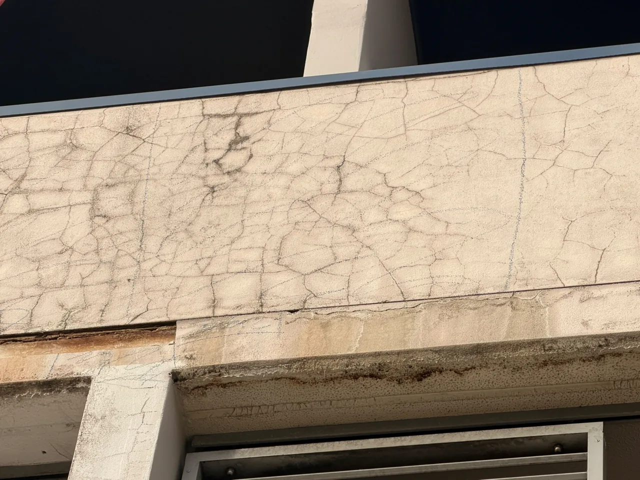 Corroding steel reinforcement bar exposed along the edge of a concrete balcony slab
