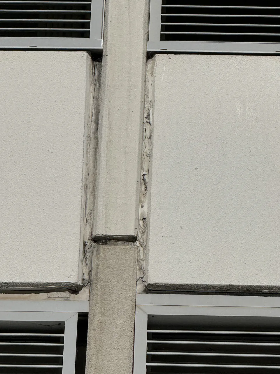 Cracked and perished sealant along a vertical control joint between facade panels