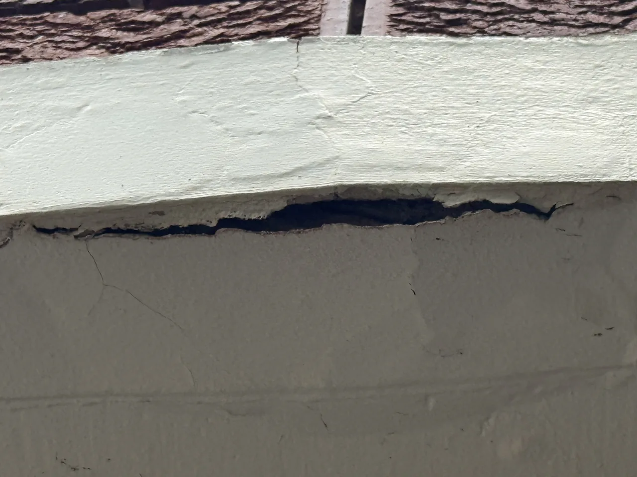 Painted parapet with a long horizontal split where render has debonded from the substrate