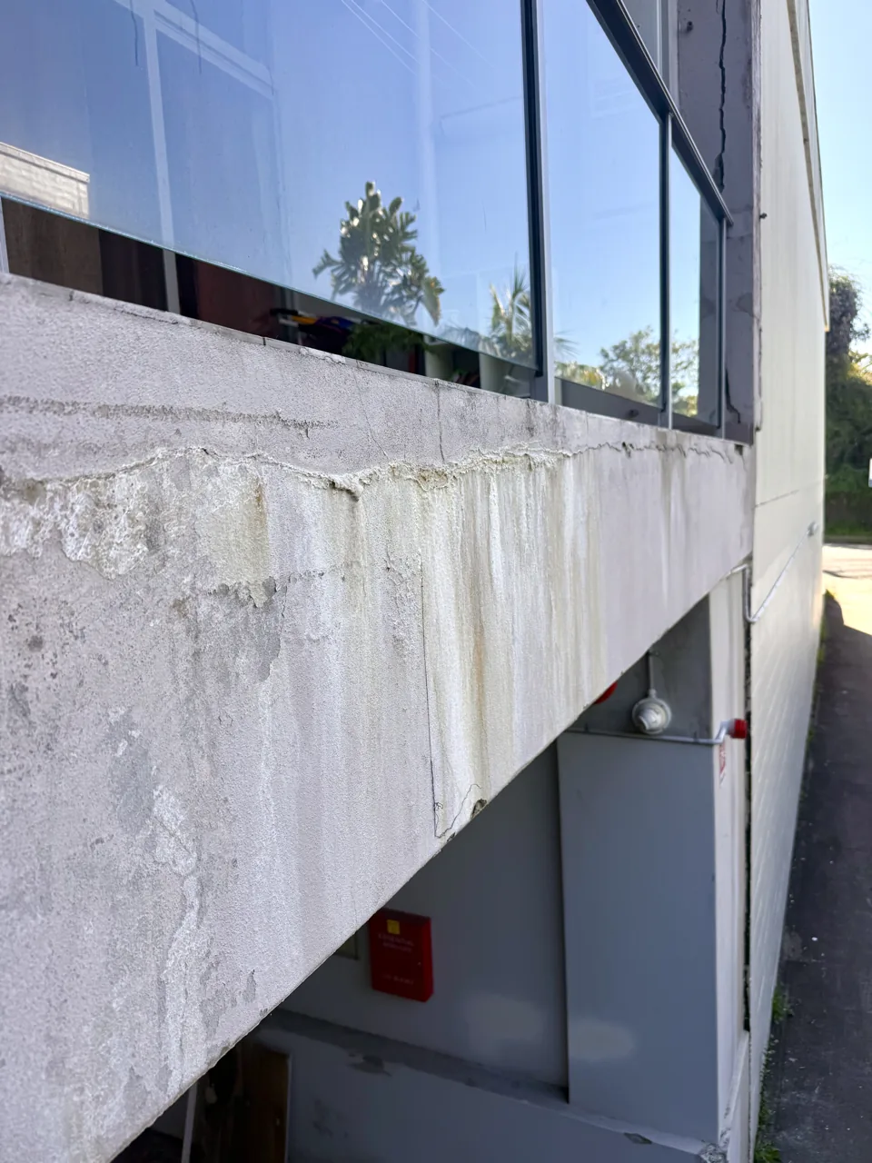 Corroding steel reinforcement bar exposed along the edge of a concrete balcony slab