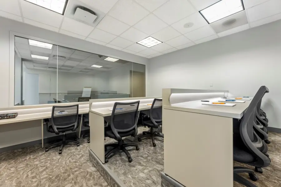 Spacious client viewing room behind a one-way mirror in the O'Hare suite at L&E Research Chicago, featuring tiered seating and built-in workspaces.