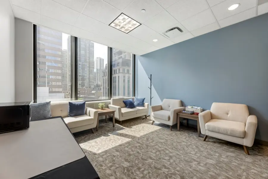 Modern executive client lounge at L&E Research's 10,000-square-foot Chicago facility, equipped with desks, office supplies, and HD streaming monitors.
