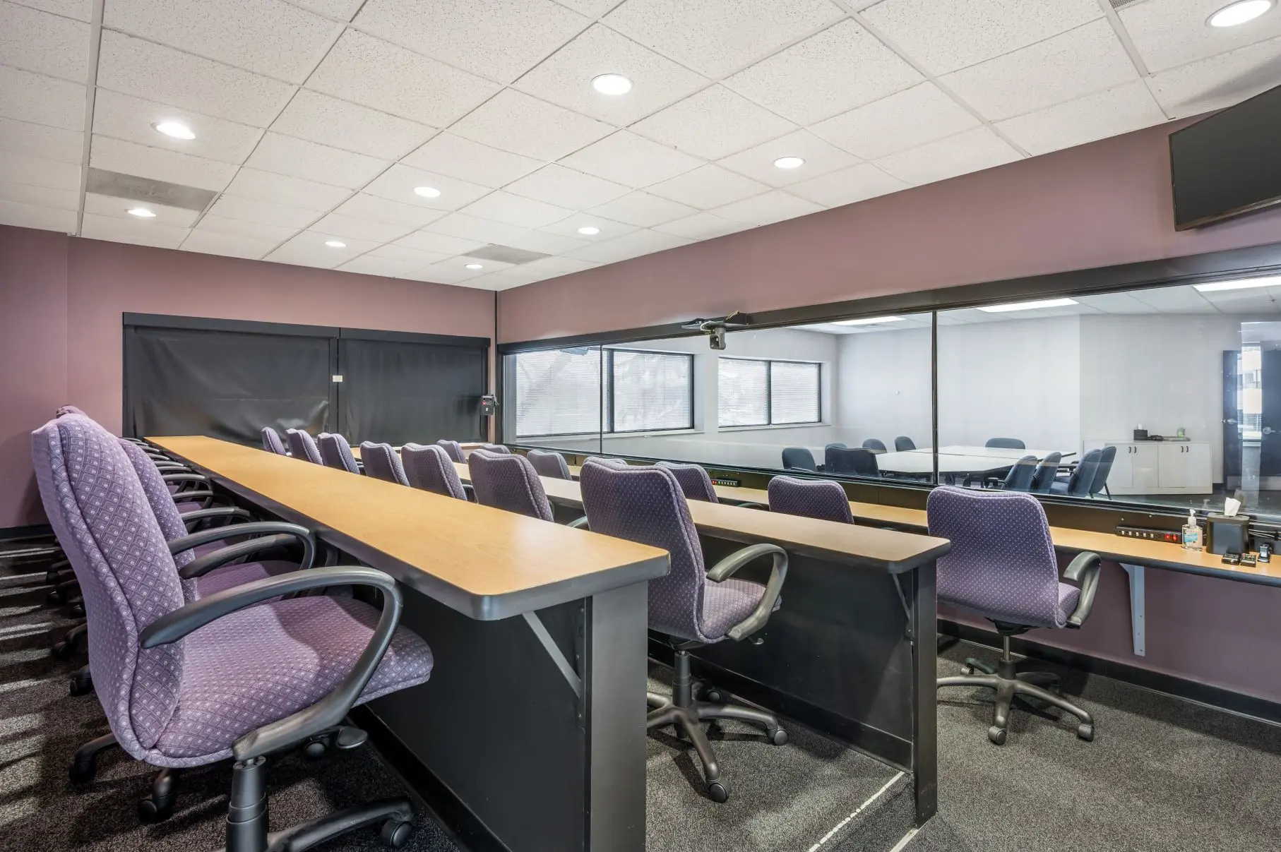 Client viewing room behind a large one-way mirror overlooking the Mt. Adams participant panel room at L&E Research Cincinnati.