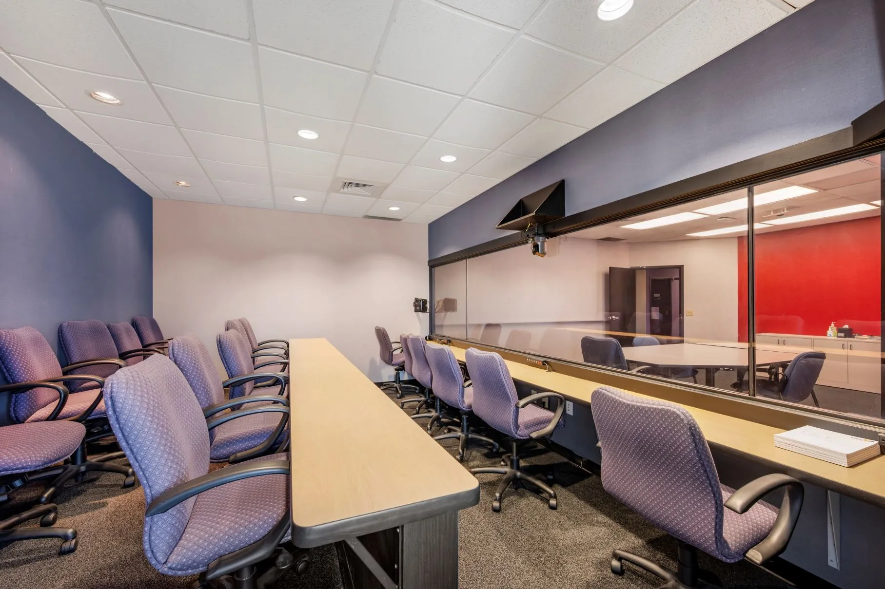 Discreet client observation booth with tiered seating behind a one-way mirror in the Blue Ash suite at L&E Research Cincinnati.