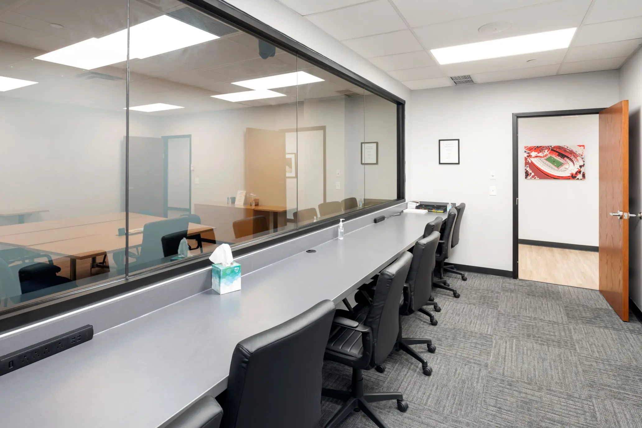Standard client observation booth behind a large one-way mirror in the Capitol qualitative research suite at L&E Research Columbus.