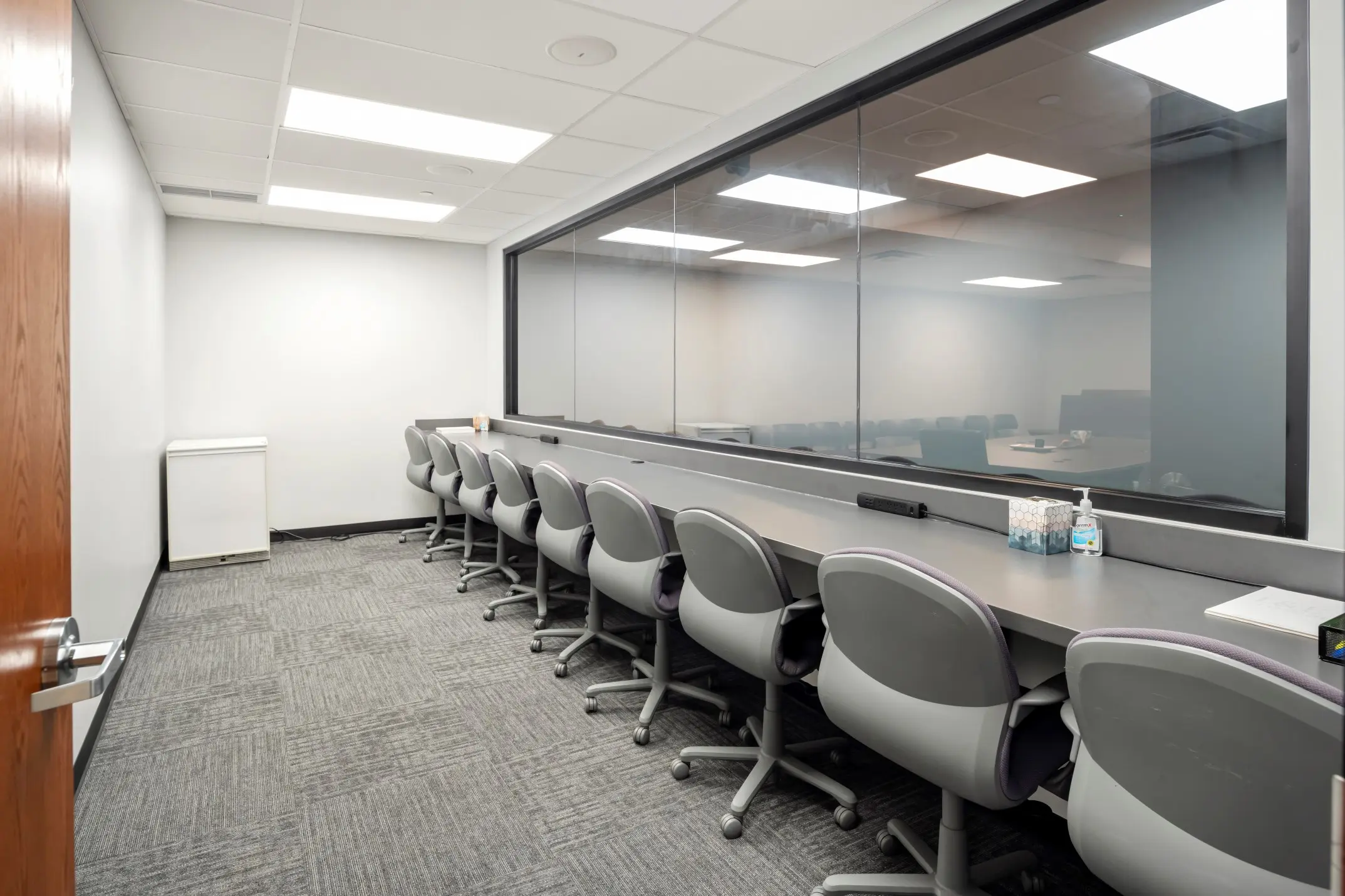 Spacious client observation room with tiered seating behind a large one-way mirror in the Buckeye suite at L&E Research Columbus.