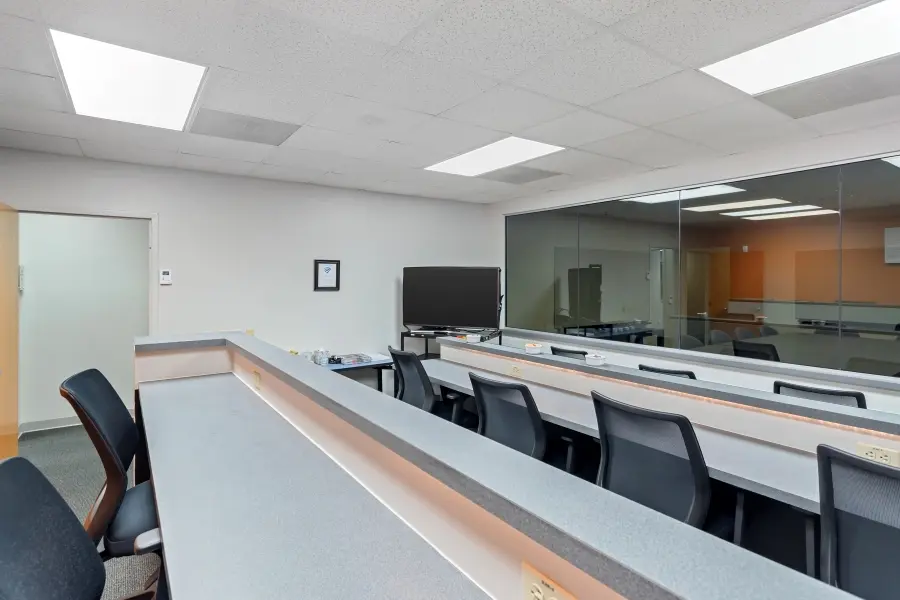 Dedicated observer viewing booth behind a large one-way mirror in the St. Petersburg qualitative research suite at L&E Research.