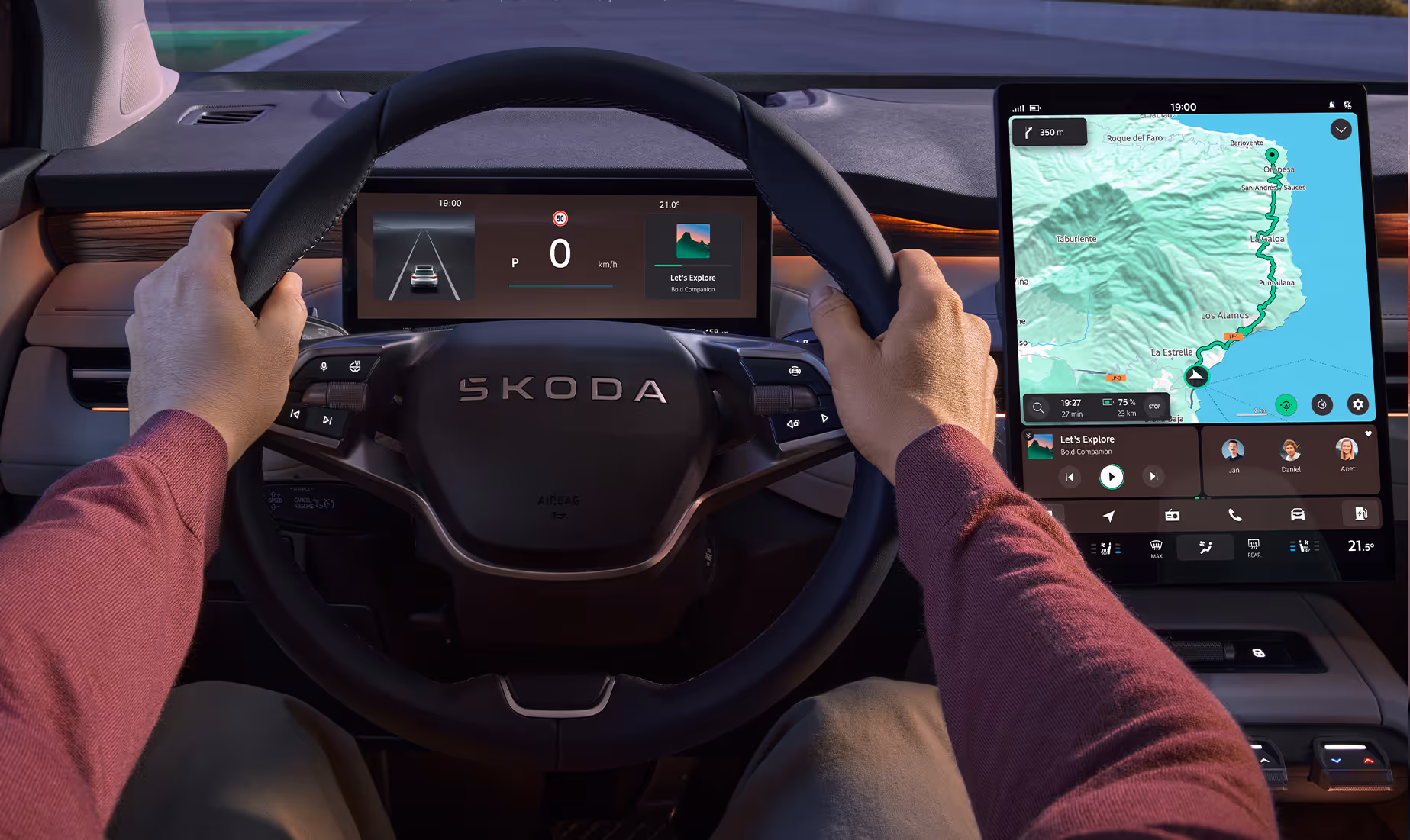 Blick aus der Fahrerperspektive in das moderne Cockpit des Škoda Peaq bei abendlichen Lichtverhältnissen. Die Hände ruhen auf dem Multifunktionslenkrad, hinter dem ein digitales Kombiinstrument sowie ein Head-up-Display auf der Windschutzscheibe wichtige Fahrdaten anzeigen. Rechts daneben ist ein großes, freistehendes Infotainment-Display mit aktiver Routenführung zu sehen, während eine warme Ambientebeleuchtung das Interieur dezent akzentuiert.