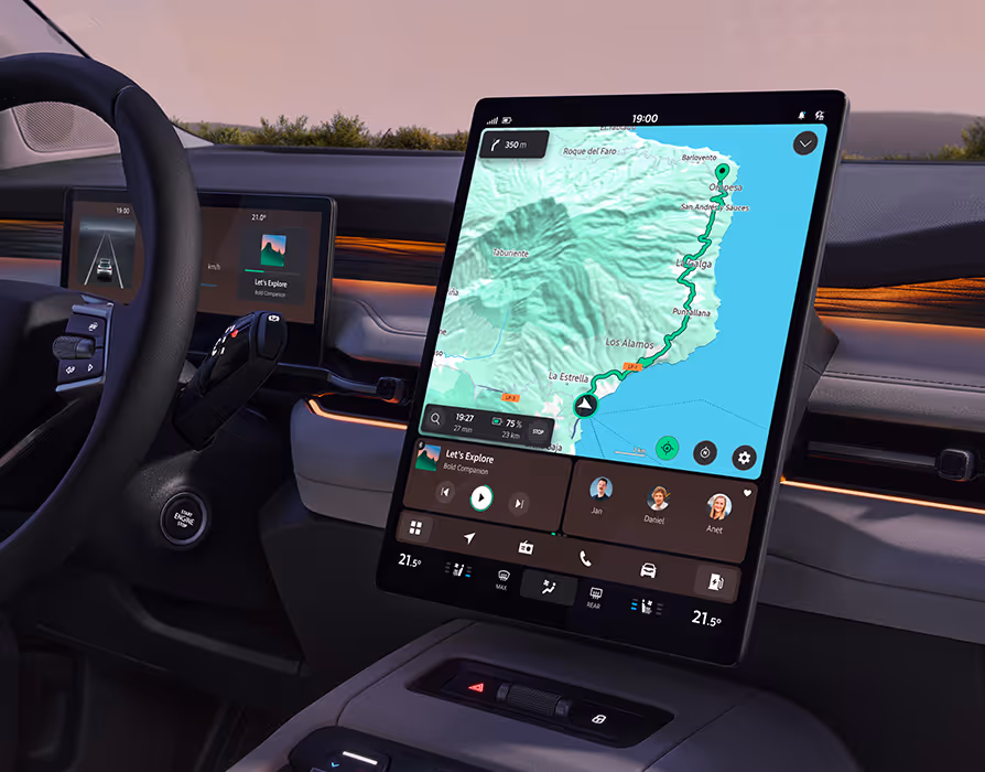 Detailaufnahme des großen, hochformatigen Infotainment-Displays im Zentrum der Armaturentafel des Škoda Peaq. Der Bildschirm zeigt übersichtlich eine aktive Kartennavigation sowie darunter angeordnete Bedienelemente für Medien, Kommunikation und Klimatisierung. Links im Hintergrund ergänzen das Multifunktionslenkrad und das digitale Kombiinstrument den modernen, mit warmer Ambientebeleuchtung akzentuierten Fahrerarbeitsplatz.