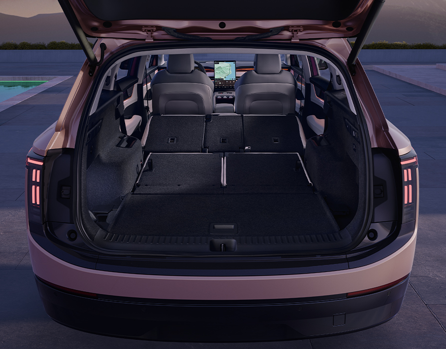 Blick in den geöffneten Kofferraum des Škoda Peaq in der Lackierung Rosewood-Beige Metallic. Durch das vollständige Umklappen der hinteren Sitzreihen entsteht eine durchgehend ebene, besonders großzügige Ladefläche für maximalen Stauraum. Der weite Blick durch den Innenraum reicht bis zu den hellen Vordersitzen und dem zentralen Infotainment-Display im Cockpit.