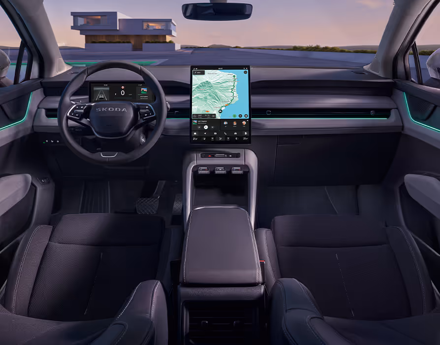 Symmetrischer Blick aus dem Fond in das aufgeräumte Cockpit des Škoda Peaq mit der dunklen Innenausstattung "Design Selection Loft". Das Interieur zeichnet sich durch graue Sitze, ein zentrales Infotainment-Display mit aktiver Navigation und ein digitales Kombiinstrument hinter dem Multifunktionslenkrad aus. Eine markante grüne Ambientebeleuchtung setzt frische farbliche Akzente entlang der Armaturentafel und den Türverkleidungen.