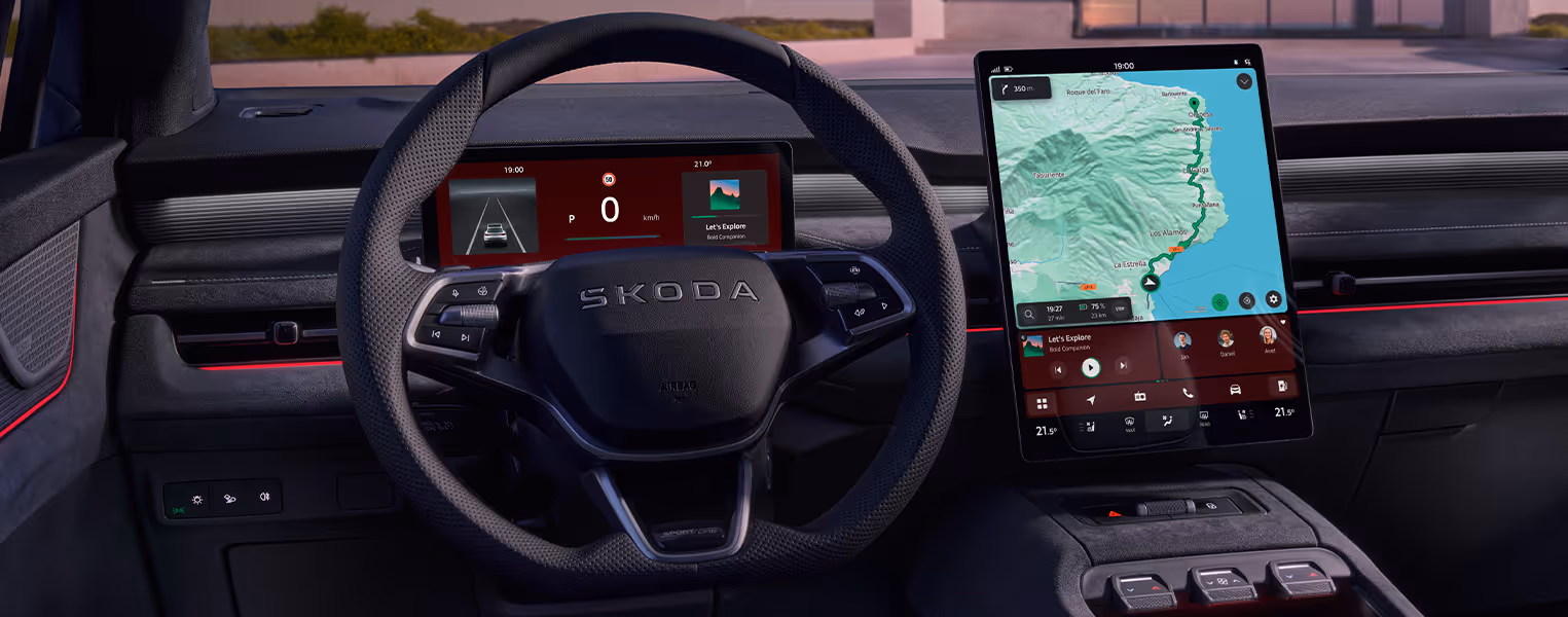 Blick aus der Fahrerperspektive in das dunkel gehaltene Cockpit des Škoda Peaq in der Ausstattungsvariante Sportline. Im Fokus stehen das unten abgeflachte Multifunktionslenkrad mit perforiertem Leder und das große, hochformatige Infotainment-Display mit aktiver Kartennavigation in der Mittelkonsole. Rote Farbakzente im digitalen Kombiinstrument sowie eine markante rote Ambientebeleuchtung entlang der Armaturentafel unterstreichen den sportlichen Charakter des Interieurs.