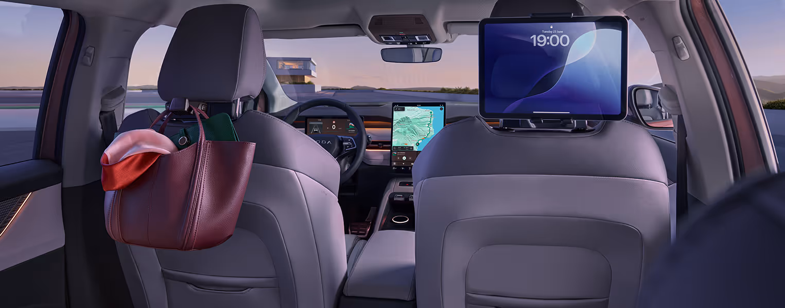 Blick aus dem Fond des Škoda Peaq auf die Vordersitze, die an den Kopfstützen mit Smart-Holder-Aufsätzen ausgestattet sind. An der linken Halterung hängt sicher und griffbereit eine dunkle Handtasche, während auf der rechten Seite ein Tablet für die Fondpassagiere eingespannt ist.
