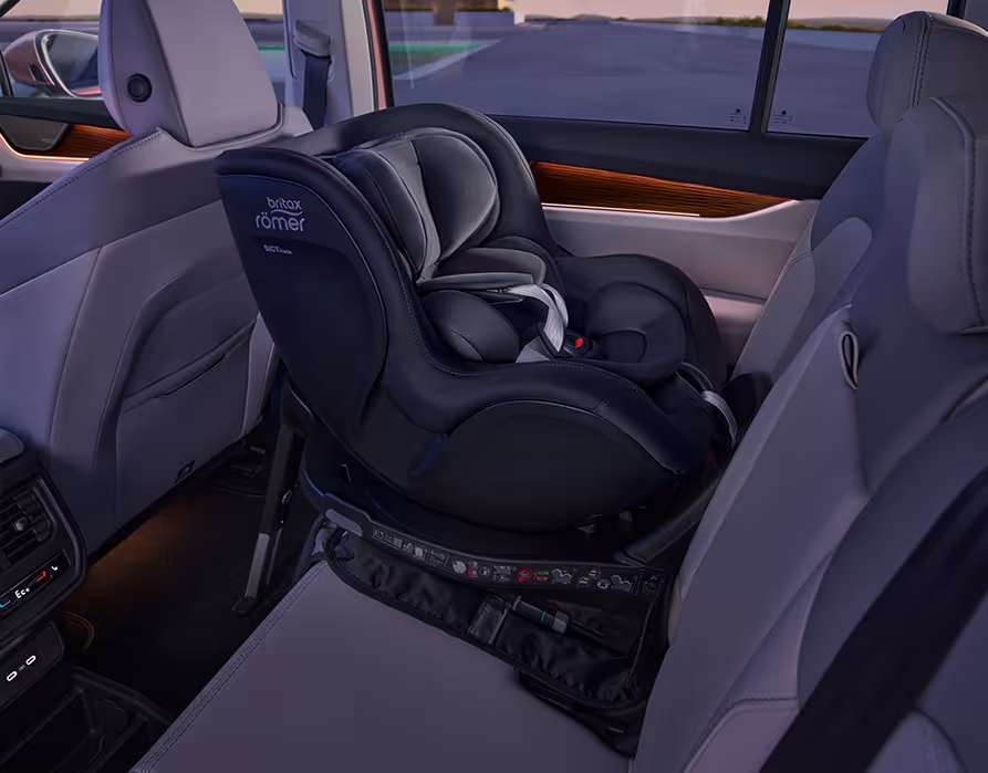 Blick in den Fond des Škoda Peaq auf die helle Rücksitzbank, auf der ein dunkler Kindersitz der Marke Britax Römer entgegen der Fahrtrichtung montiert ist. Zum Schutz der Sitzpolsterung befindet sich unter dem sogenannten Reboarder eine passgenaue, dunkle Schutzmatte. 