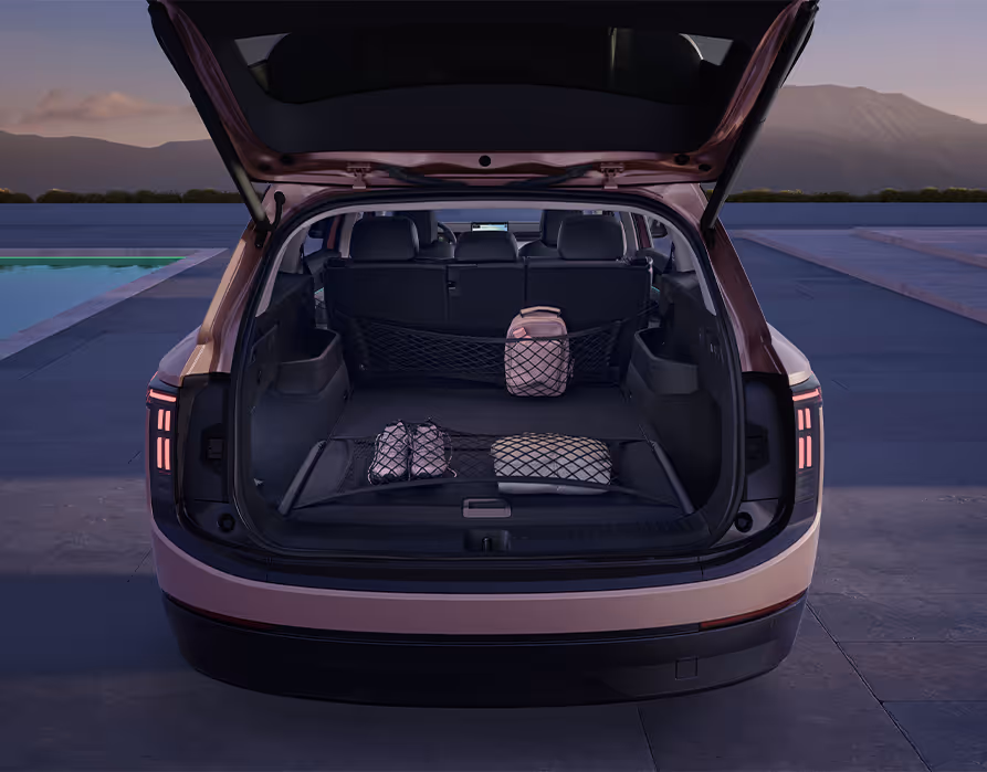 Blick in den geöffneten Kofferraum des Škoda Peaq in der Lackierung Rosewood-Beige Metallic. Ein praktisches Netzsystem sorgt auf dem dunklen Ladeboden und an der Rücksitzlehne für eine sichere Fixierung von Gegenständen wie einem Rucksack, einer kleinen Tasche und einem Paar Schuhen.