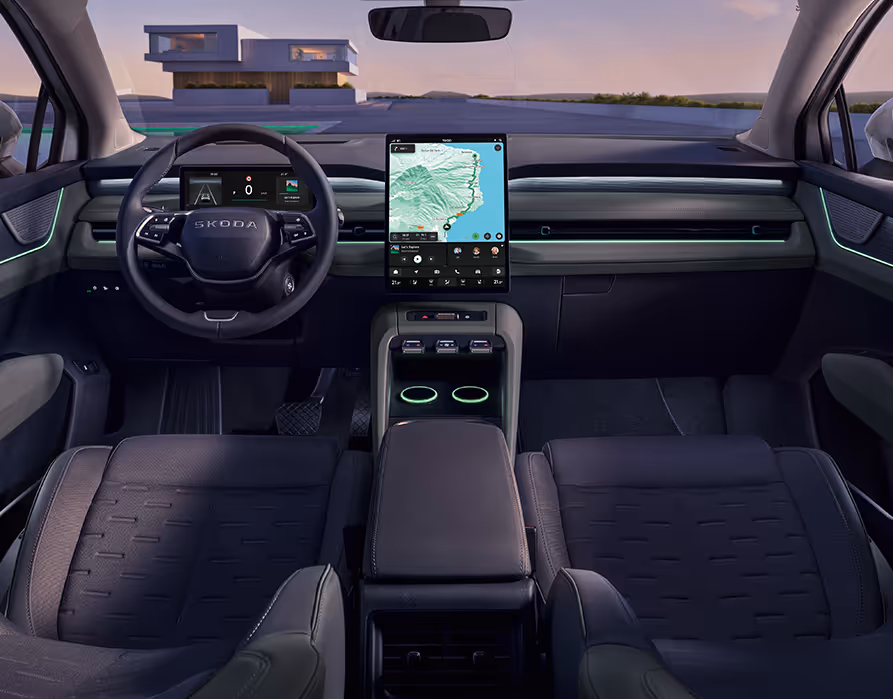 Symmetrischer Blick aus dem Fond in das Cockpit des Škoda Peaq mit der Innenausstattung "Design Selection Lodge". Das Interieur zeichnet sich durch zweifarbige Sitze mit markant gemusterten Mittelbahnen, ein zentrales Infotainment-Display mit aktiver Navigation und das Multifunktionslenkrad aus. Eine frische grüne Ambientebeleuchtung entlang der Armaturentafel setzt im abendlichen Licht klare farbliche Akzente im Innenraum.