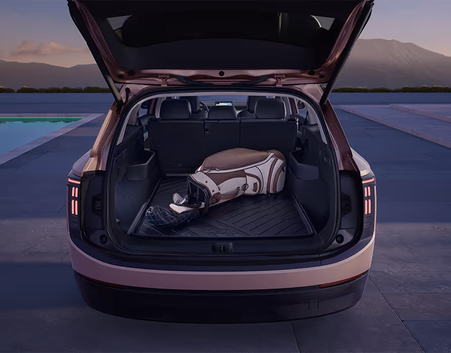 Blick in den geöffneten Kofferraum des Škoda Peaq in der Lackierung Rosewood-Beige Metallic. Auf dem Ladeboden, der mit einer strukturierten, dunklen Gummimatte vor Schmutz geschützt ist, liegt quer eine große Golftasche. Die Ansicht veranschaulicht das großzügige Platzangebot des Gepäckraums, das auch bei aufgestellter Rücksitzbank ausreichend Raum für sperriges Freizeitgepäck bietet.